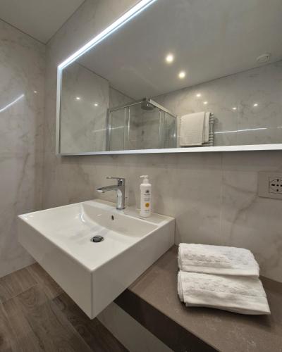 a white bathroom with a sink and a mirror at Libra Aparthotel in Bibione