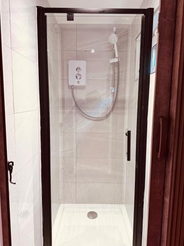 a shower in a bathroom with a glass door at Golden Oak Guest House in North Leigh