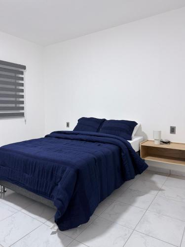 a bedroom with a bed with a blue blanket at Belisario Apartment in Ocotlán