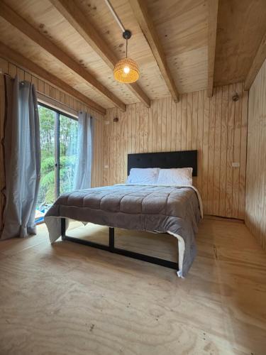 a bedroom with a bed in a room with wooden walls at Tiny House A & M Chaiten in Chaitén