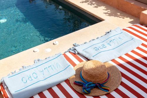 a hat and two towels on a table next to a swimming pool at Villa Oro in Oia