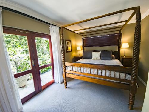 a bedroom with a canopy bed and a window at Shepherd's Corner Guest House - Tranquil Boutique Stay in Bryanston in Johannesburg
