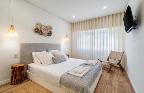a bedroom with a bed with a television and a chair at Brisa do Mar in Quarteira