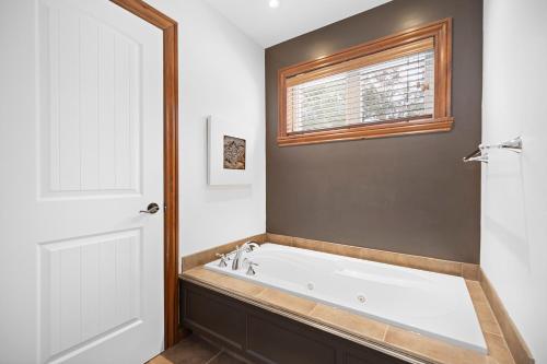 a bath tub in a bathroom with a window at Townhouse On The Golf La Bte -10min To Tremblant in Mont-Tremblant