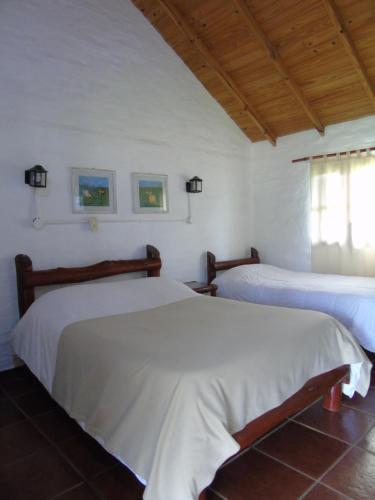 two beds in a room with white walls at Iberá Porá in Colonia Carlos Pellegrini