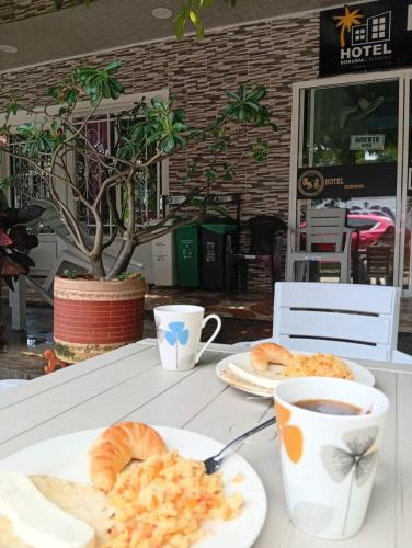 a table with two plates of croissants and a cup of coffee at Hotel vacation Doradal in Doradal