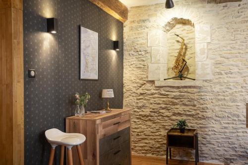 a bathroom with a stone wall with a vanity and a stool at Le Millésime in Dijon