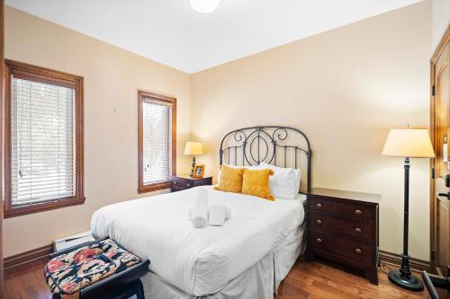 a bedroom with a large white bed and two windows at House On The Golf La Bte -10min To Tremblant 150 in Mont-Tremblant