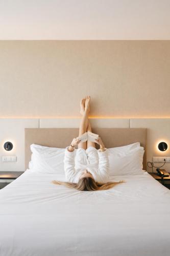 a woman laying on a bed with her legs in the air at Oporto Fly Hotel in Maia