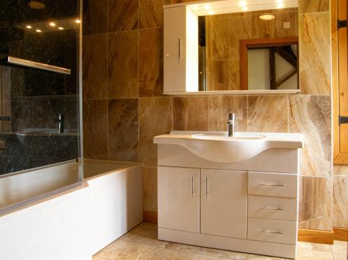 a bathroom with a sink and a mirror and a tub at Tyn Y Celyn Canol in Clocaenog