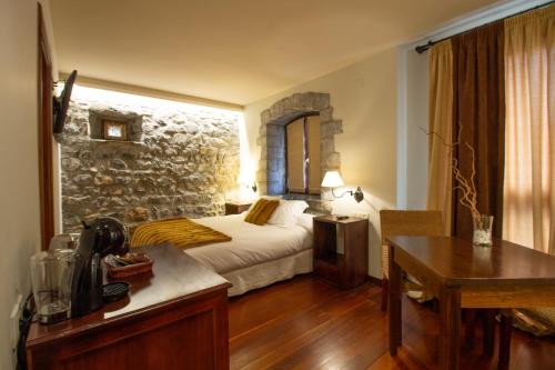 a bedroom with a bed and a stone wall at HOTEL EL Alboroque in Tramacastilla de Tena