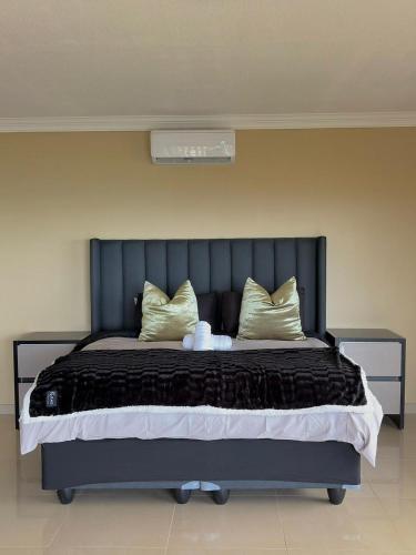 a bedroom with a large bed with black sheets and gold pillows at Oceanview Oasis in Freeland Park
