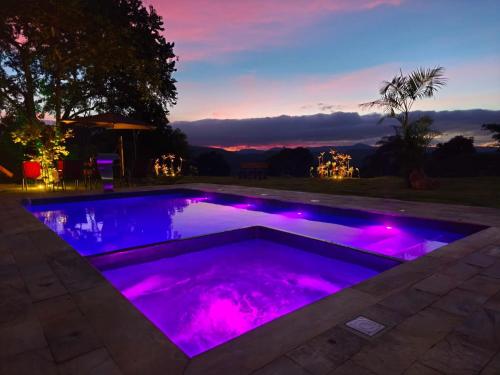 a pool with purple lights in a backyard at night at Recanto da Natureza in Itabirito