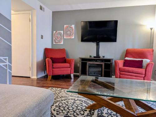 a living room with two red chairs and a television at Exclusive Townhome - Central Raleigh Location in Raleigh