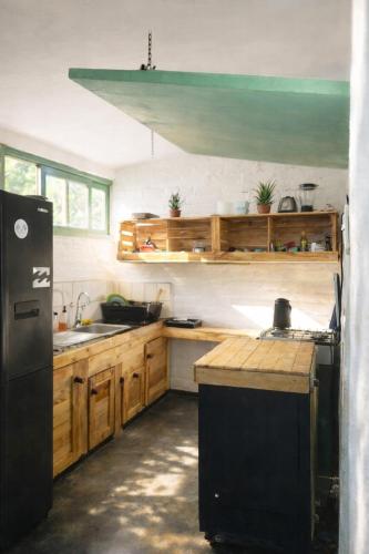a kitchen with wooden cabinets and a black refrigerator at Viento Este Guest House in Popoyo