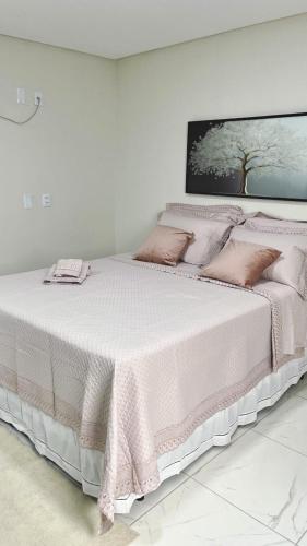 a white bedroom with a large bed with pink sheets and pillows at Hotel Pedra da Letra in Mauriti