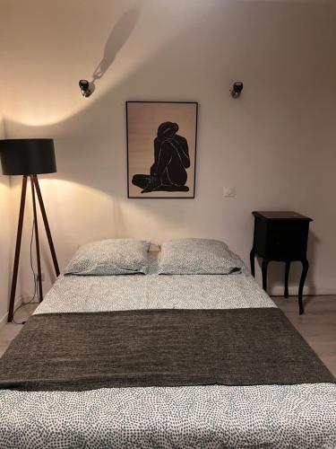 a bedroom with a bed and a lamp and a table at 3- Le saule mauve in Poitiers