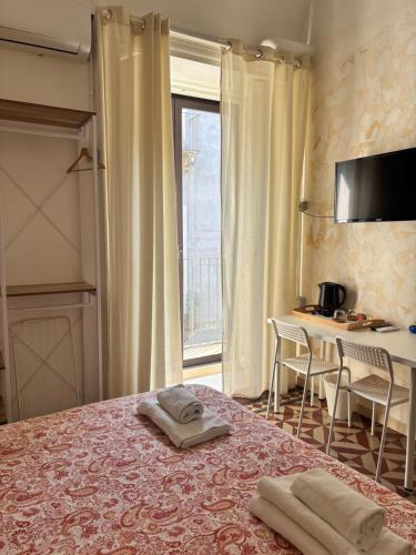a hotel room with a bed with two towels on it at Il Teatro Rooms in Catania