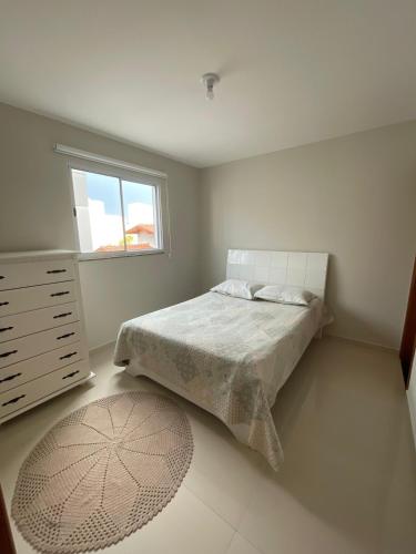 a bedroom with a bed and a window and a rug at Apartamento em Poços - Varanda com Churrasqueira in Poços de Caldas