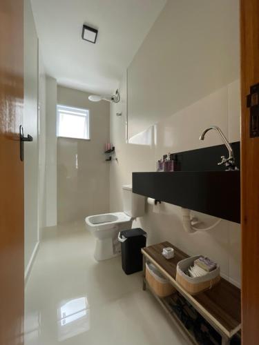 a white bathroom with a toilet and a sink at Apartamento em Poços - Varanda com Churrasqueira in Poços de Caldas