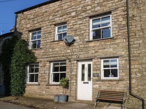 a brick building with a white door and a bench at Hillside View in Hawes