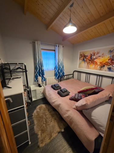 a bedroom with a large bed and a window at Secluded Log Cabin escape in High Wycombe