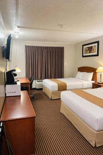 a hotel room with two beds and a desk at Northern Lights Inn & Suites in Valleyview