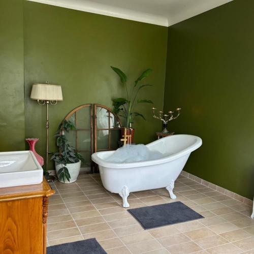 a bathroom with a tub and a green wall at Private floor in Molkom