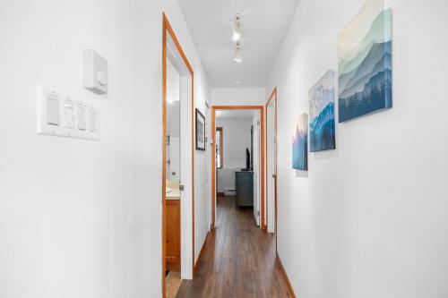 a hallway with white walls and paintings on the walls at Hauts-bois Ski Inout 2brs Wpool Access 197-9 in Mont-Tremblant