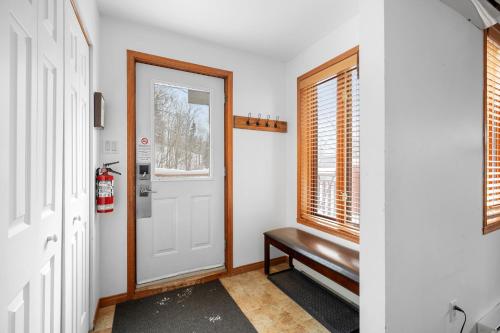 a hallway with a door and a bench next to a window at Hauts-bois Ski Inout 2brs Wpool Access 197-9 in Mont-Tremblant