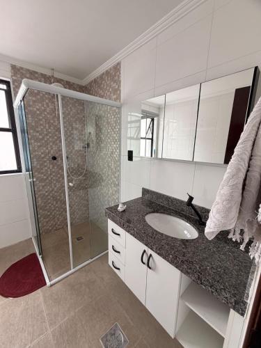 a bathroom with a sink and a shower at Flat Romance Praia e Home Office in São Vicente