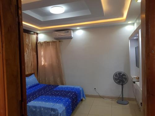 a room with a blue bed and a fan at Résidence BEDEL in Yamoussoukro