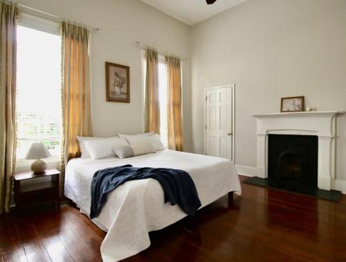 a white bedroom with a bed and a fireplace at Macons Historic Tatnall Home in Macon