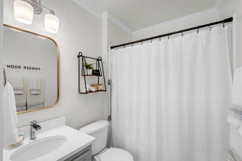 a white bathroom with a toilet and a sink at Cottages at Oak Park in Ocean Springs