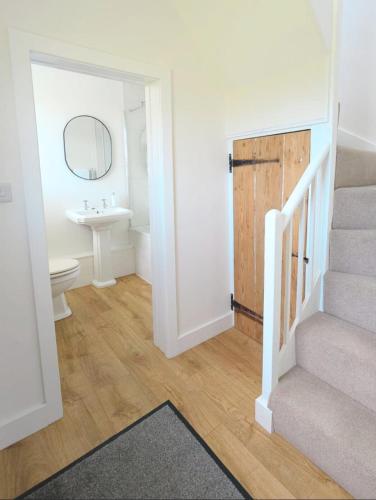 a bathroom with a sink and a stairway with a toilet at Rural Retreat near West Wittering Beach! Dog Friendly & Free Parking - Ideal Weekend Getaway! Chichester Holiday Properties in Donnington