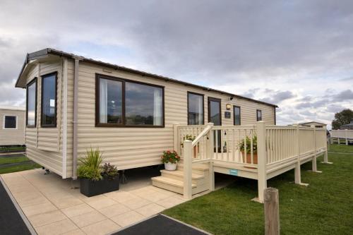 a tiny house with a porch and a deck at Tattershall Caravan- 28 The Pastures in Tattershall