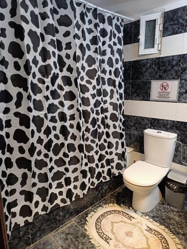 a bathroom with a black and white shower curtain and a toilet at Erofili's Apartment ONLY 700 meters from the beach in Ialysos
