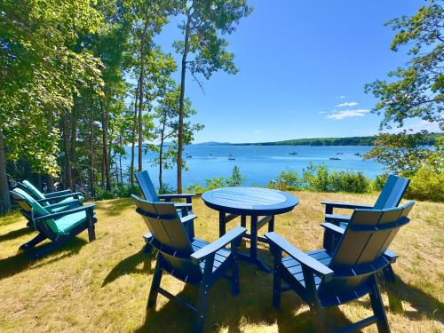 a table and chairs with a view of a lake at Lucky Stone Retreat - private beach & Acadia view in Sullivan