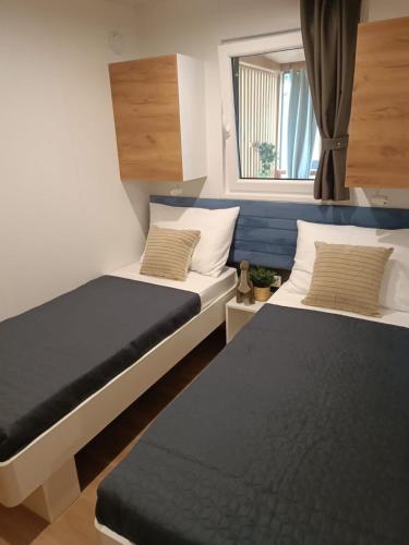 two beds in a small room with a window at Max Mobile Home in Biograd na Moru