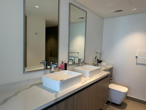 ein Badezimmer mit zwei Waschbecken, einer Toilette und einem Spiegel in der Unterkunft Beachfront Villa with Heated Private Pool & Jacuzzi in Al Ḩamrīyah