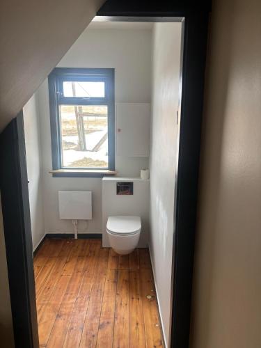 a small bathroom with a toilet and a window at Grjótá Historical countryhouse in Hvolsvöllur