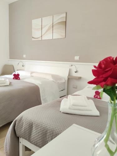 a bedroom with two beds and a vase with red flowers at B&B Alle porte del centro in Santa Maria Capua Vetere