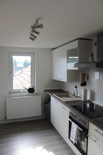 a white kitchen with a sink and a window at Fewo HARZ Benneckenstein in Benneckenstein