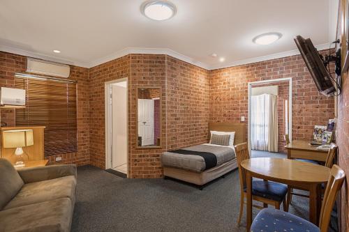 a living room with a bed and a table at Akuna Motor Inn and Apartments in Dubbo