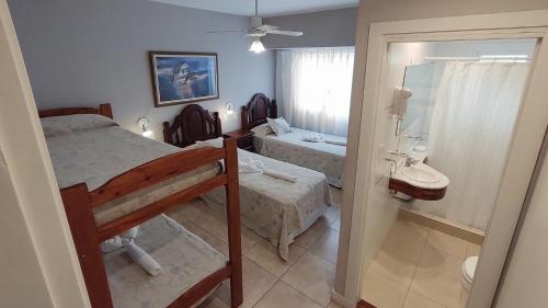 a bedroom with a bed and a bathroom with a sink at Hotel Rideamus in Villa Gesell