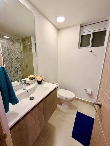 a white bathroom with a toilet and a sink at Apartamento en Villeta in Villeta