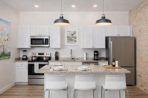 a kitchen with white cabinets and a counter with chairs at Luxury Downtown 2 Bedroom Flat in Neenah