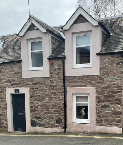 a brick house with a dog in the window at Meadow Cottage in Crieff