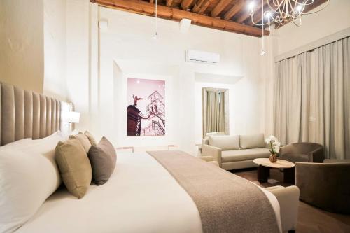 a bedroom with a large white bed and a living room at Quinta Real Puebla in Puebla