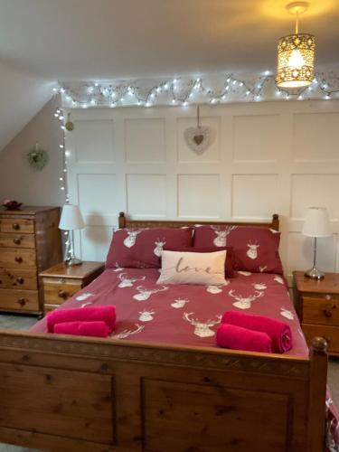 a bedroom with a large bed with red sheets at Meadow Cottage in Crieff
